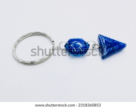 A blue colour,hexagon and triangle shape keytag on white background.It has blue colour glitter, silver keychain.It made of resin material.This picture was taken from the side of the keytag.Beautiful.