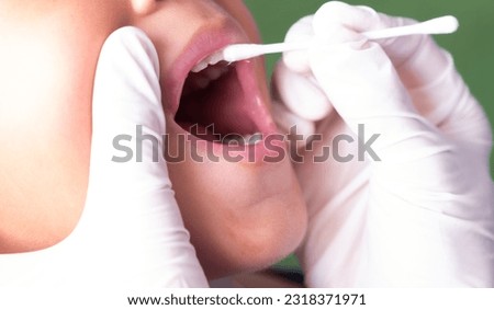 A dentist applies fluoride varnish to children to prevent tooth decay. Royalty-Free Stock Photo #2318371971