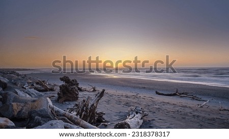 Last light at the empty Hokitika beach and the tasman sea. The sea wave are choppy here. The beach is is filled with deadwood and tree trunks. The sun is above to descend below the horizon Royalty-Free Stock Photo #2318378317