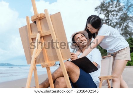Young couple relaxing by the sea in the morning sit and paint with watercolors as a hobby