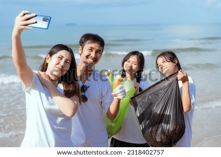 A group of young men and women volunteers stand to take pictures in a smiling group. Clean up the trash and water bottles on the beach.