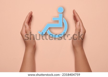 Disability inclusion. Woman protecting wheelchair symbol on pale pink background, closeup