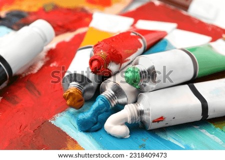 Tubes of colorful oil paints on canvas with abstract painting, closeup