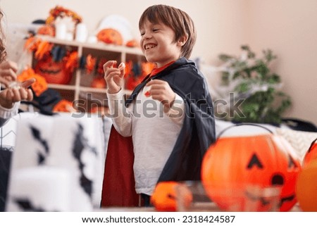 Adorable caucasian boy wearing vampire costume holding sweets at home
