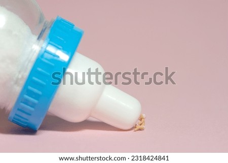 Miniature tiny people toy figure photography. A boy toddler infant drinking a milk of bottle. Isolated on pink background. Image photo