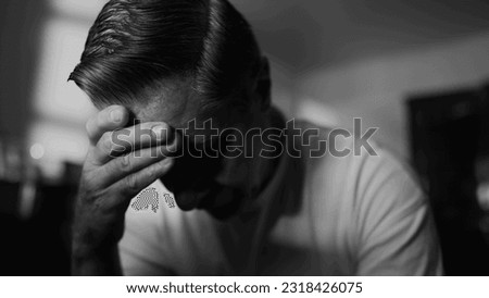Older man struggling with trauma and loneliness. Middle-aged male person covering face looking down in shame and despair. Hopeless feeling depicted in monochrome black and white Royalty-Free Stock Photo #2318426075