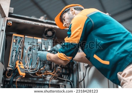 Electrical technician tests wiring, polarity, grounding, voltages and performs electrical maintenance using hand tools that involve clamp meter, screwdriver, and cutter. The foreman's routine tasks. Royalty-Free Stock Photo #2318428123