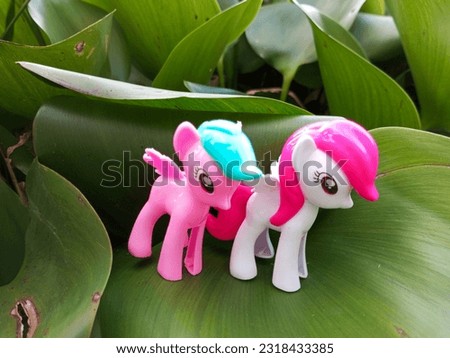 two children's toy horses, pink and white on a hyacinth leaf