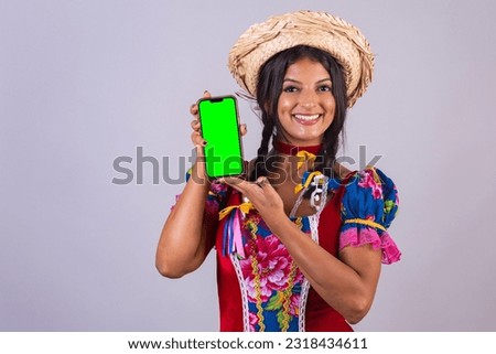 brazilian woman with clothes from festa de são joão, festa junina. With smartphone, green screen.