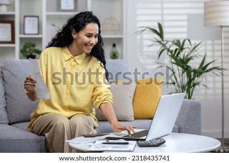 Smiling young beautiful woman reading banking paper notification about last mortgage payment while calculating budget at home. Happy hispanic girl feeling excited of good news in letter notice Royalty-Free Stock Photo #2318435741