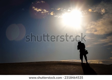 A photographer stands on a dune in the desert, getting his shots, near Horizon City just east of El Paso, Texas.