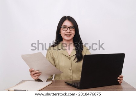 Female teacher in civil servant uniform with paper and laptop on the desk Royalty-Free Stock Photo #2318476875
