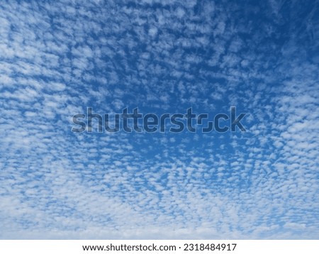 Blue sky with unusual abstract white clouds structure. Strange dramatic clouds pattern texture.