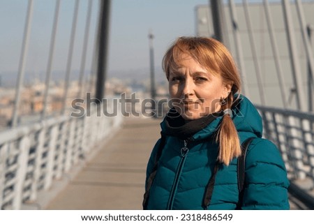 A girl in a green autumn jacket on a bridge on a sunny day. Pedestrian bridge on suspension ropes. Royalty-Free Stock Photo #2318486549