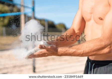 photo detail of shirtless athletic man putting magnesium in his hands - photo detail of arms and hands with magnesium - calisthenics training concept