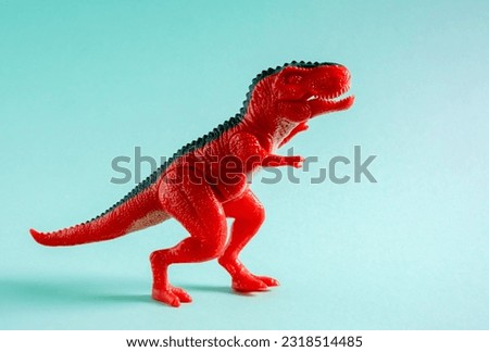 Red dinosaur toy on blue background.