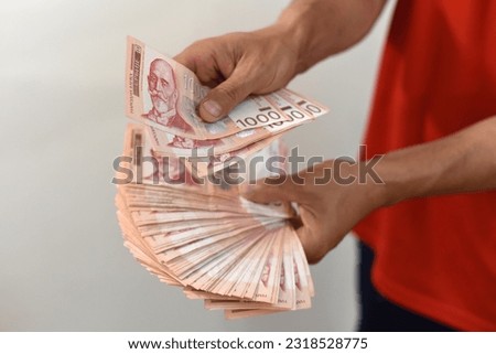 Hands holding pile of money. Serbian dinar paper currency, 1000 dinars value Royalty-Free Stock Photo #2318528775