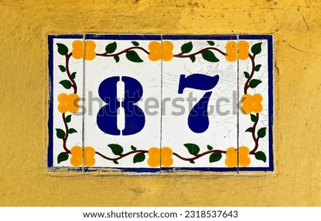 Street sign number 87 on a yellow wall
