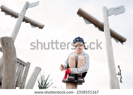 Little boy is playing as a pirate on the wooden playground. 