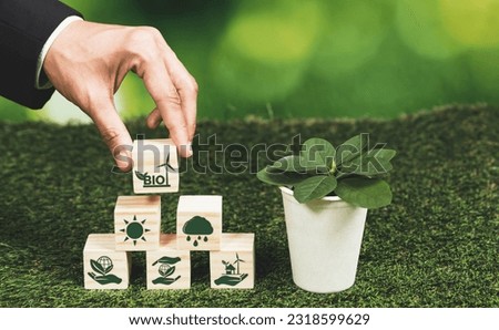 Businessman's hand holding eco-concern symbol on wooden cube and plant pot. Eco-friendly bio fuel from plants or waste for alternative sustainable and clean bio energy to preserve eco future. Alter