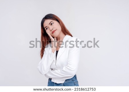 A problematic young woman with one hand to her cheek and head tilted while looking to the left in deep thought. Isolated on a white background. Royalty-Free Stock Photo #2318612753