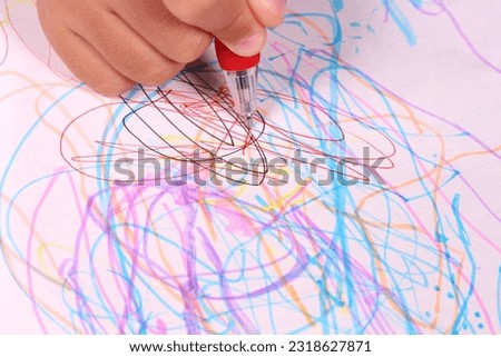 Child drawing with ballpoint pen on white paper, close-up