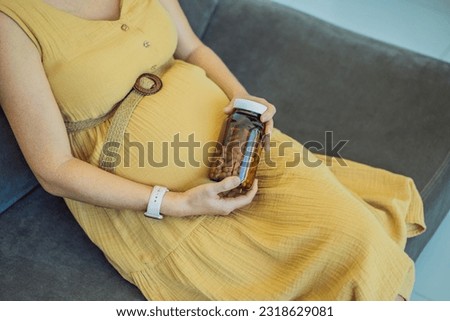 Prenatal Vitamins. Portrait Of Beautiful Smiling Pregnant Woman Holding Transparent Glass Jar With Pills, Taking Supplements For Healthy Pregnancy While Sitting On Couch At Home, Free Space Royalty-Free Stock Photo #2318629081