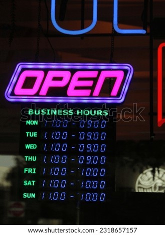 Vintage Neon Open Sign at Night With Hours Displayed