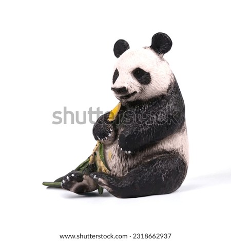 Close-up of a miniature toy panda eating on a white background