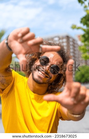 Portrait of an afro-haired man in a yellow t-shirt. Portrait in the city smiling on summer vacation Royalty-Free Stock Photo #2318673025
