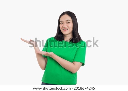 Smiling asian woman pointing finger to the right side with product or empty copy space standing over isolated white background wearing green t-shirt