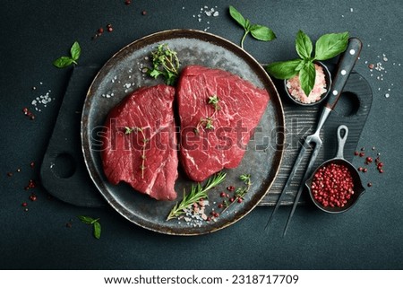 Juicy raw piece of selected veal on a plate with spices and herbs, on a stone background. Veal, steak. Top view. Royalty-Free Stock Photo #2318717709