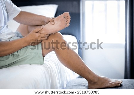Asian middle aged man massaging his sole of the foot,suffering from Plantar fasciitis,foot pain problem,inflammation of the fascia of muscle,painful and stiffness in feet and heels,sore in ankle joint Royalty-Free Stock Photo #2318730983