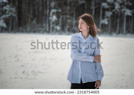 Portrait of a young beautiful girl in the snow in winter outdoors.