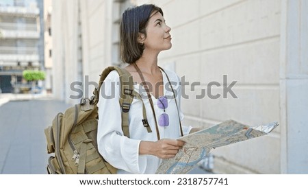 Young beautiful hispanic woman tourist smiling confident holding city map at street