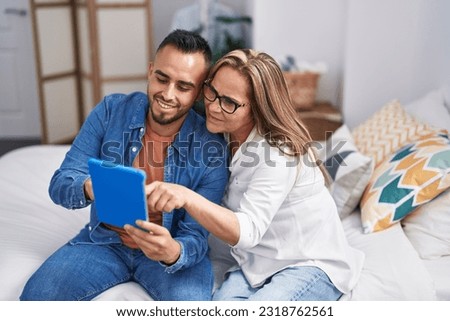 Man and woman mother and son using touchpad at bedroom