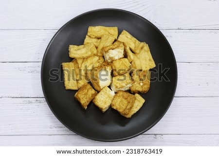 Deep Fried Tofu in black plate, top view white wood texture background