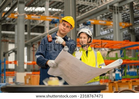 Factory workers man and woman discuss about the project using drawing paper or plan in workplace with machine and product shelves are in the background. Royalty-Free Stock Photo #2318767471