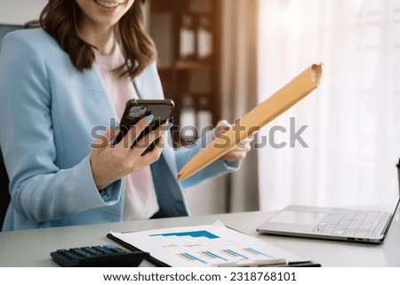 Business woman working at office with smartphone and documents on his desk, financial adviser analyzing data.