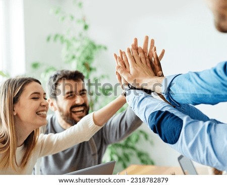 A portrait of young businesspeople celebrating with high five in the office Royalty-Free Stock Photo #2318782879