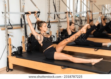 Group of young women exercising on pilates reformers beds Royalty-Free Stock Photo #2318787225