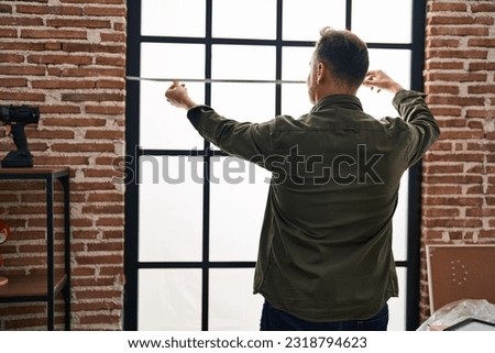 Young caucasian man measuring window at new home