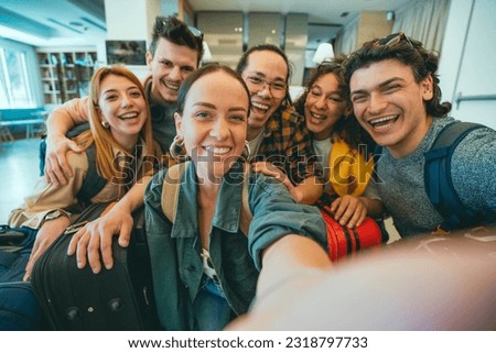 Group of young tourists standing in youth hostel guest house - Happy multiracial friends booking summer vacation home - Guys and girls having fun taking selfie picture at summertime holidays 