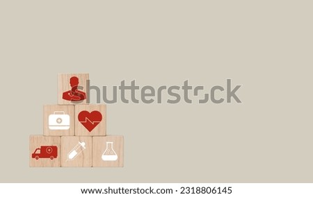 The square wooden blocks concept of health. There are red heart icons,  syringes, a pill bag, a doctor icon, and an ambulance on a gray background, leave a blank space to insert text