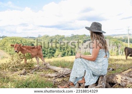 South American farmer sitting on a stump on the ranch and smiling