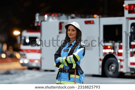 A portrait of a woman in a firefighter uniform with crossed arms, background of a nighttime street where a fire truck is seen after an intervention.