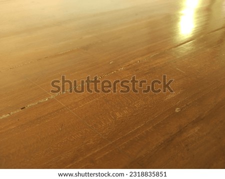A crack on the surface of a wooden desk in the office, glossed with its natural colour, defocused.