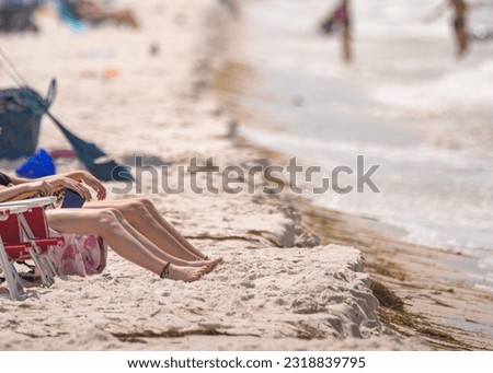legs and bare feet of young women tanning in sand at Mexico Beach, Florida, forgotten coast, emerald, wide horizontal frame