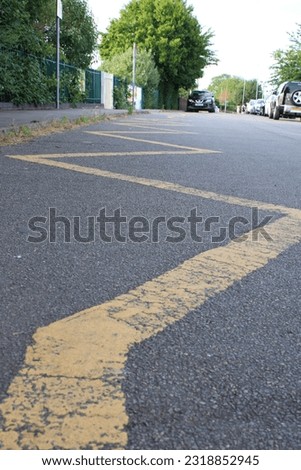 Yellow Zig Zag lines indicating to motorists to keep clear no parking taken outside school entrance UK Royalty-Free Stock Photo #2318852945