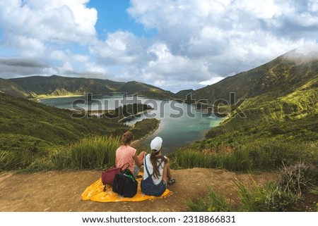 Rear view of two friends on hill top against beautiful summer landscape with forest and lake in summer. Tourists admiring wonderful nature in Azores. Vacation concept Royalty-Free Stock Photo #2318866831